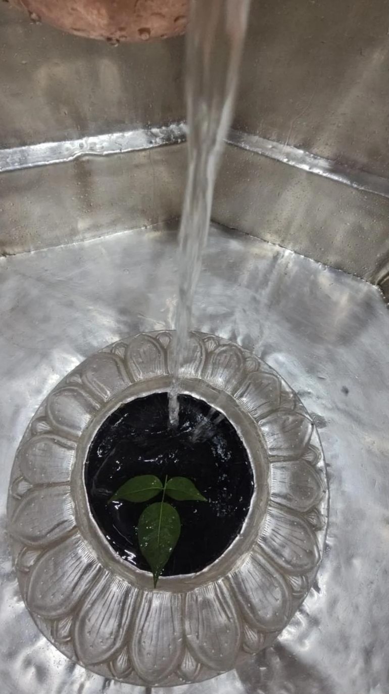 Ganga jal flowing over the Shivling, a bel patra resting in the water